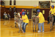 3 people trying to get on their donkeys while the man riding his donkey carries the basketball